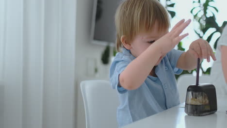 boy sharpening a pencil sitting at the table