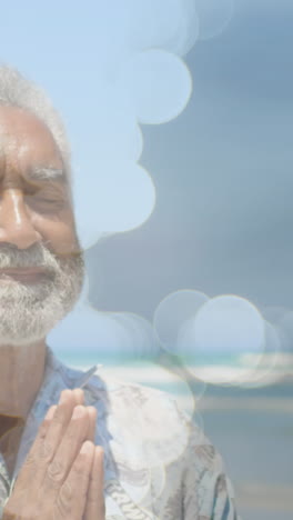 animation of light spots over senior biracial man practicing yoga and meditating