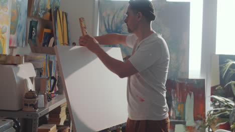 artist setting canvas in easel