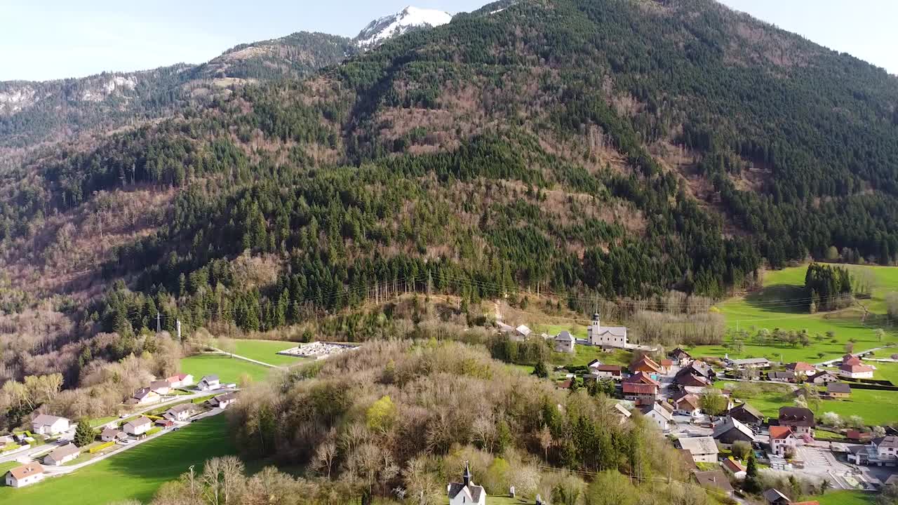 reveladora toma de drone de una capilla en la cima de una colina frente a las montañas alpinas