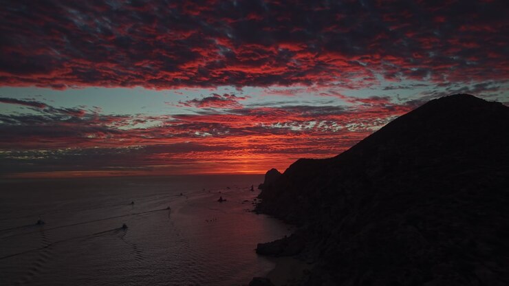 A nostalgic aerial view of an epic sunset with red clouds on the horizon, taken from Cabo San Lucas in the Gulf of Baja California, Mexico