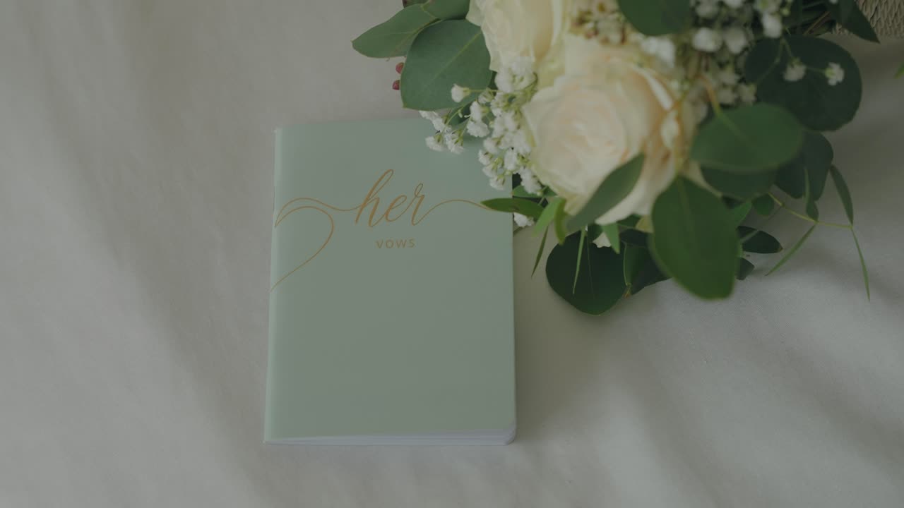 Libro de votos matrimoniales delicado decorado con flores sobre tela neutra