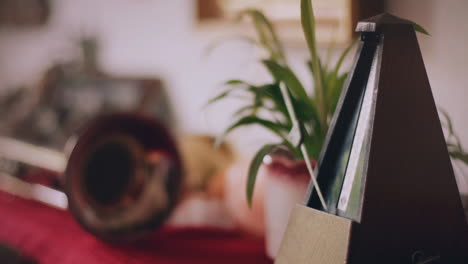 ticking metronome in warm home interior with trumpet and plant in background. cinemagraph video loop