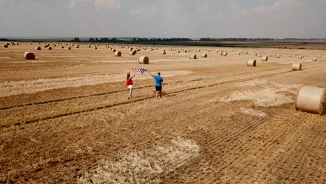 couple with american flag in hay bale field