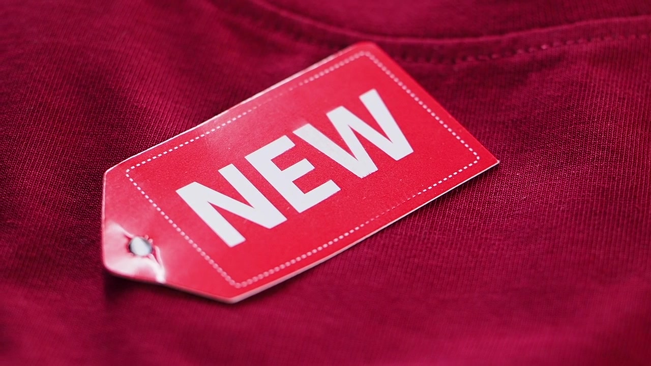 Primo piano di un'etichetta rossa "NUOVO" su tessuto di abbigliamento