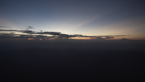 4k static shot of nice clouds and colorful sky from a flying commercial airplane window after sunset or before sunrise