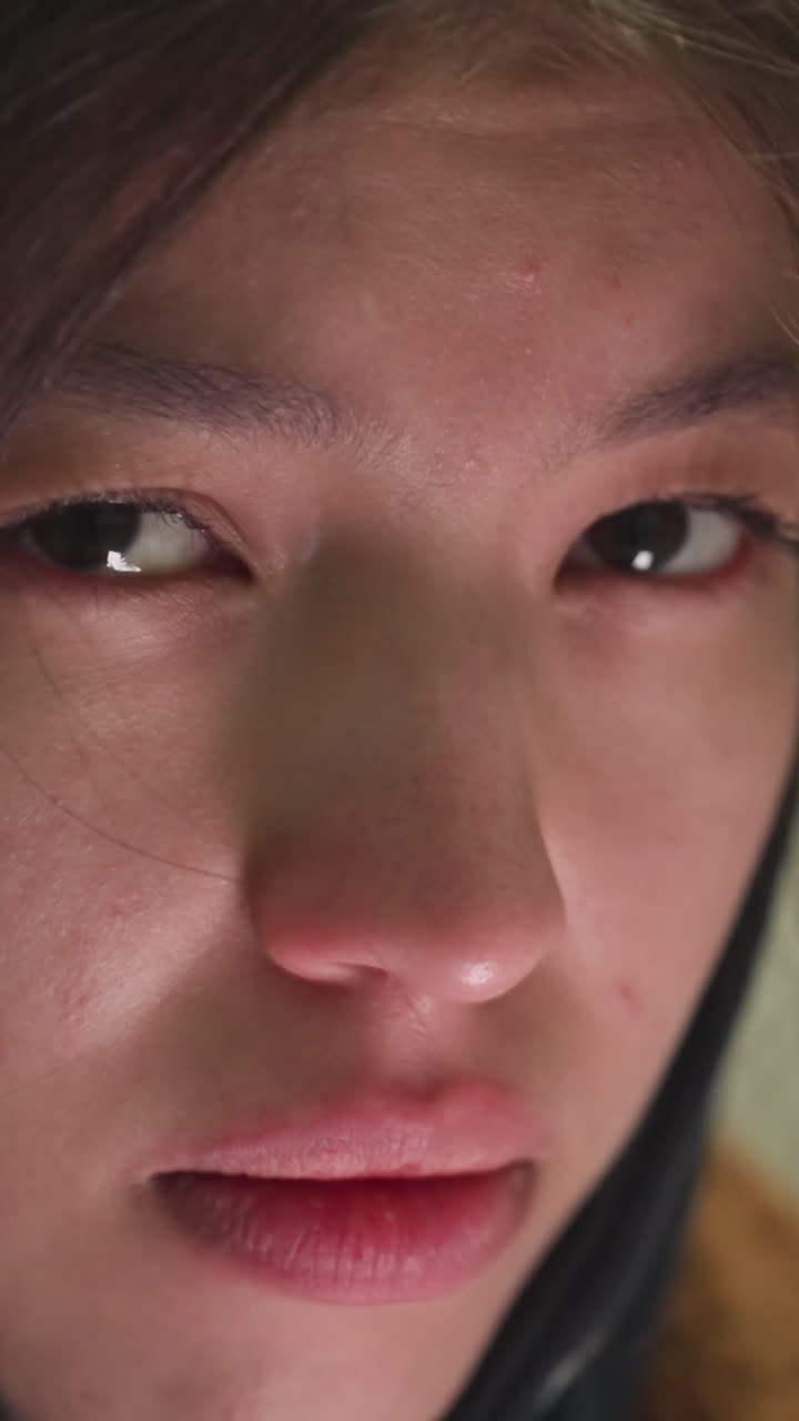 걱정스러운 표정을 가진 어린 소녀의 얼굴의 클로즈업, 그녀의 눈은 깊은 우려 또는 숙고를 반영하여 아래로 던집니다. 은 그녀의 감정의 미묘한 세부 사항을 포착합니다.