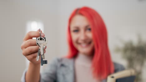 shot of apartment keys extended on hand toward camera, pink-haired woman dressed in suit holds documents and hands over keys, real estate agent, flat owner, receiving room for use