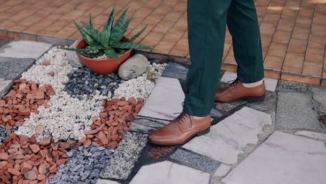 hombre elegante vestido formalmente en el detalle de la pasarela del jardín texturizado