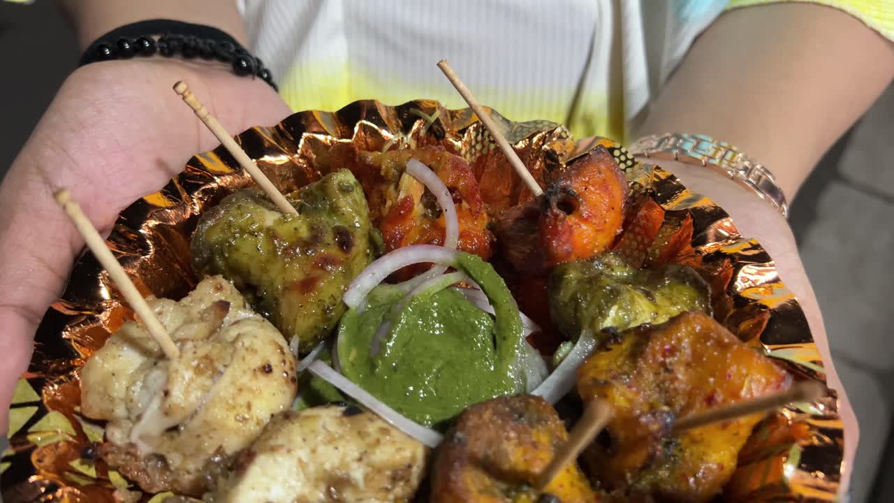 un tiro de kebabs de pollo servido en un plato a una mujer en calcuta, india