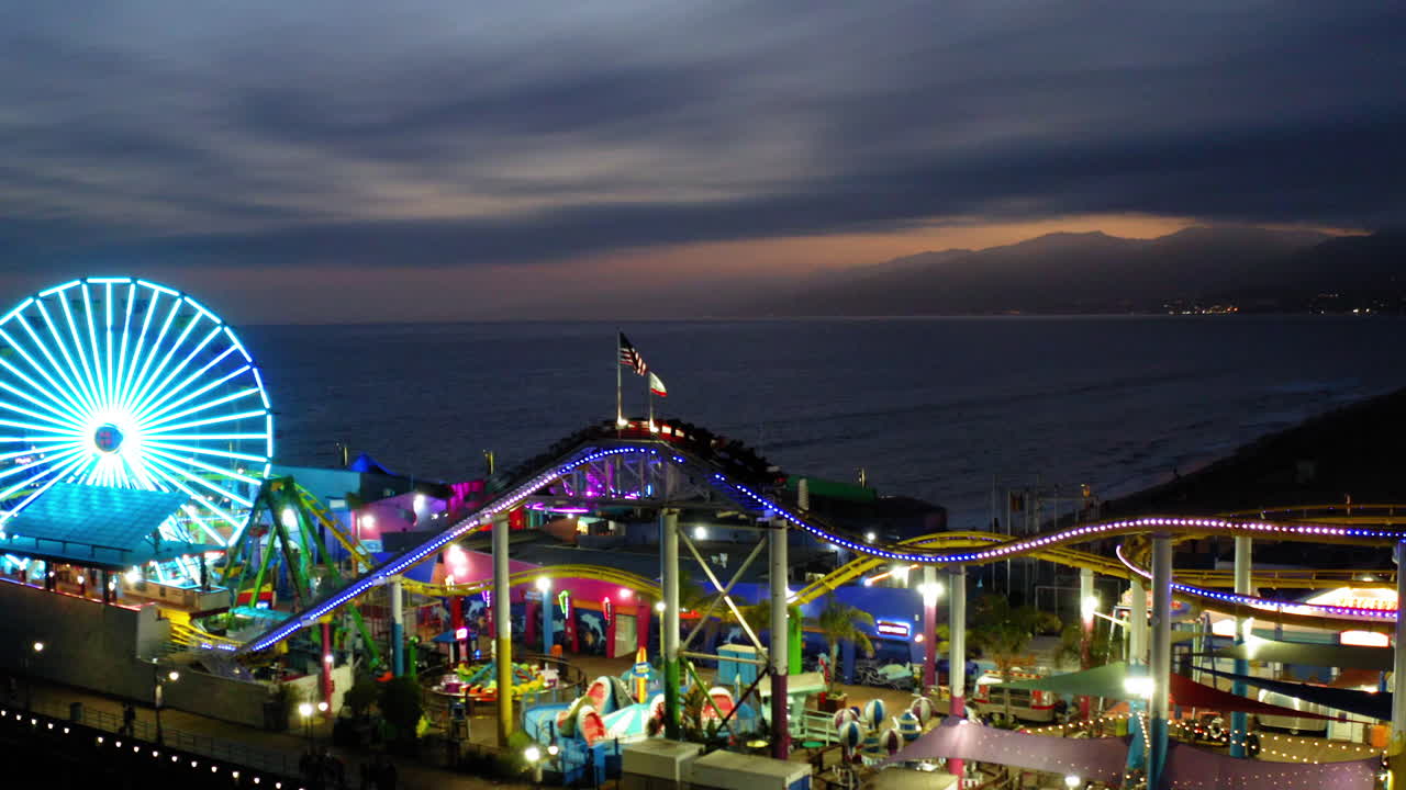 Santa Monica Pier at Dusk with Illuminated Ferris Wheel and Roller Coaster