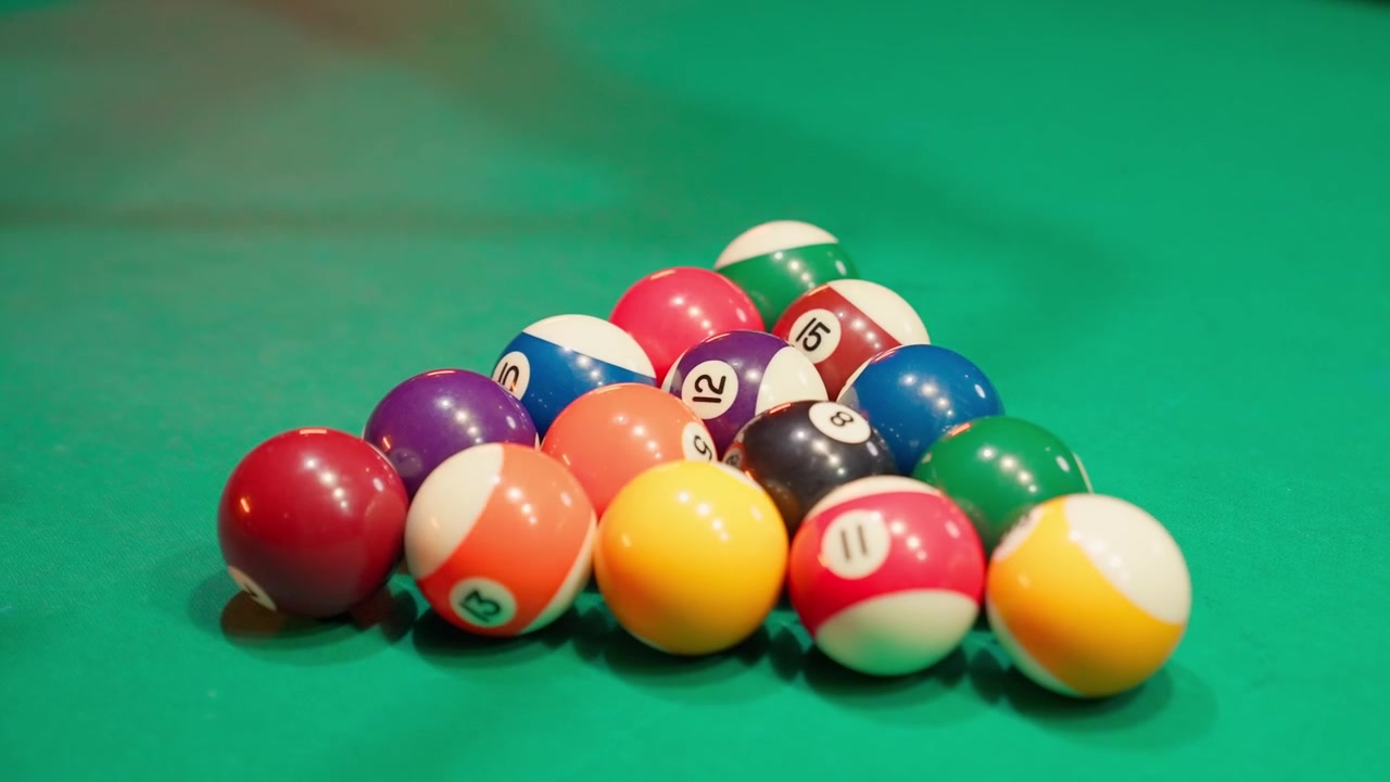 Hands Racking Billiard Balls on a Green Pool Table
