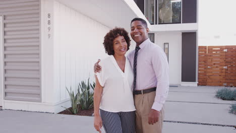 happy black middle aged couple standing together outside their modern home