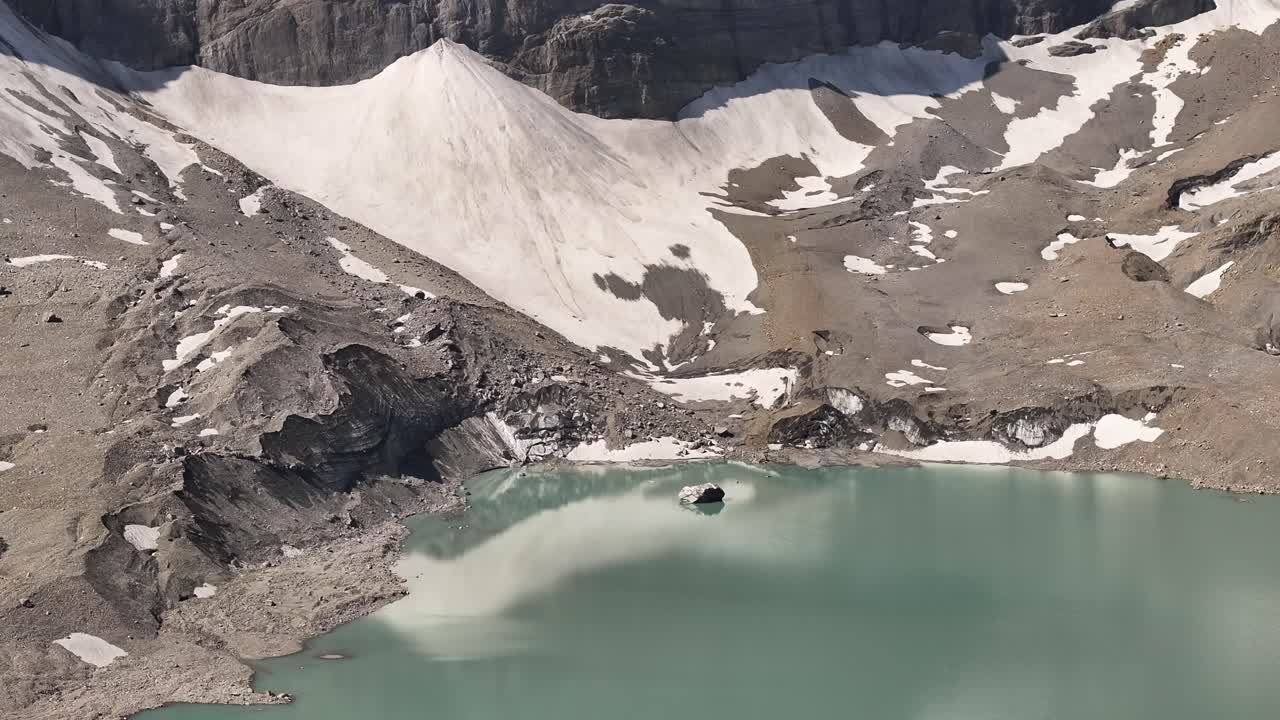Drone view of Urnerboden. Alpine mountains covered in snow with a lake of water forming