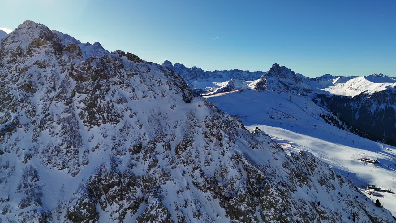 Kışın İtalyan Dolomitleri'nde çekilen, bir dağın arkasından arka plandaki manzarayı gösteren açığa çıkarma çekimi (drone çekimi).