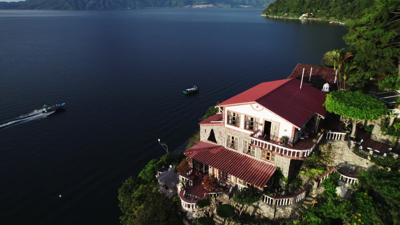 vista cinematográfica de un albergue a orillas del lago con un volcán y un barco conduciendo