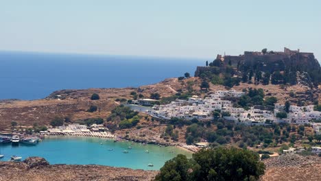Lindos-beach-overlooking-Acropolis-ruins-Castle-in-Rhodos,-Greece,-travel-destination-filmed-in-4K-during-the-day