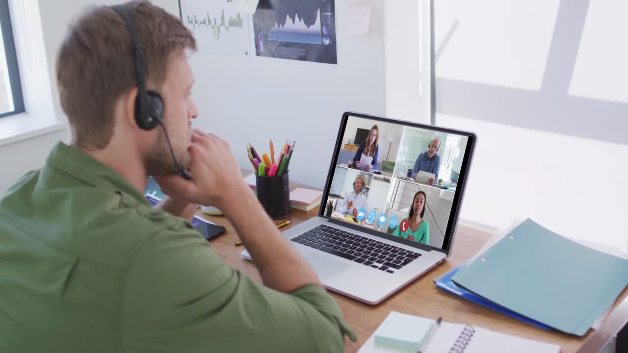 Kaukasisk mand bruger bærbar computer og telefonheadset på videoopkald med kolleger