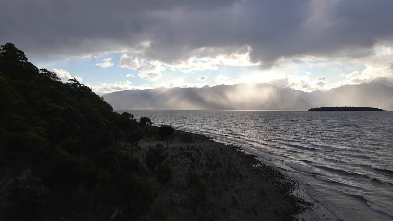 impresionantes rayos de sol que se asoman detrás de las nubes sobre el lago te anau en nueva zelanda