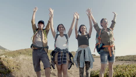 front view of family standing on cliff edge, waving hands in joy