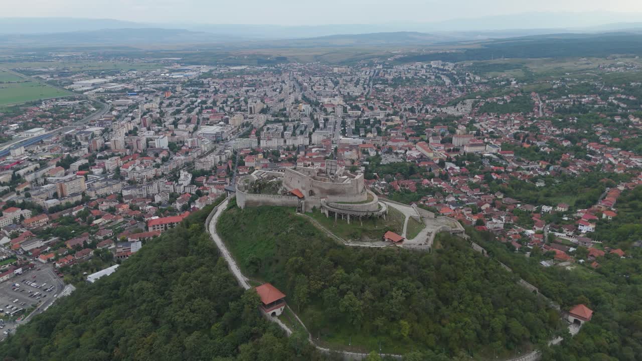 Historic Fortress of Deva perched on a hilltop, with the cityscape spreading out in the background