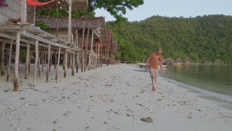 Un-Hombre-Camina-Por-La-Playa-De-Arena-De-La-Isla-Kri-En-El-Archipiélago-De-Raja-Ampat,-Indonesia