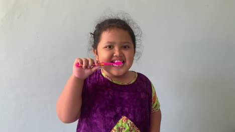 niña asiática feliz de pie mientras se cepilla los dientes