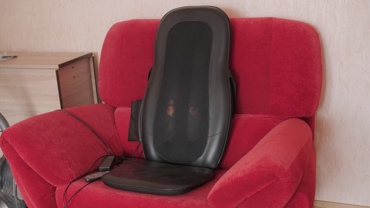 Cuscino massaggiante elettrico in funzione su una poltrona rossa.