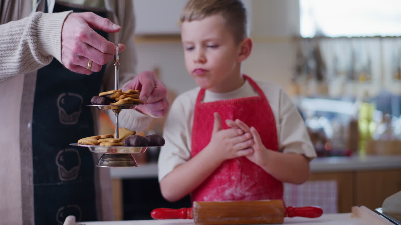 el niño sabe el pan de vacaciones mientras trabaja en la cocina.