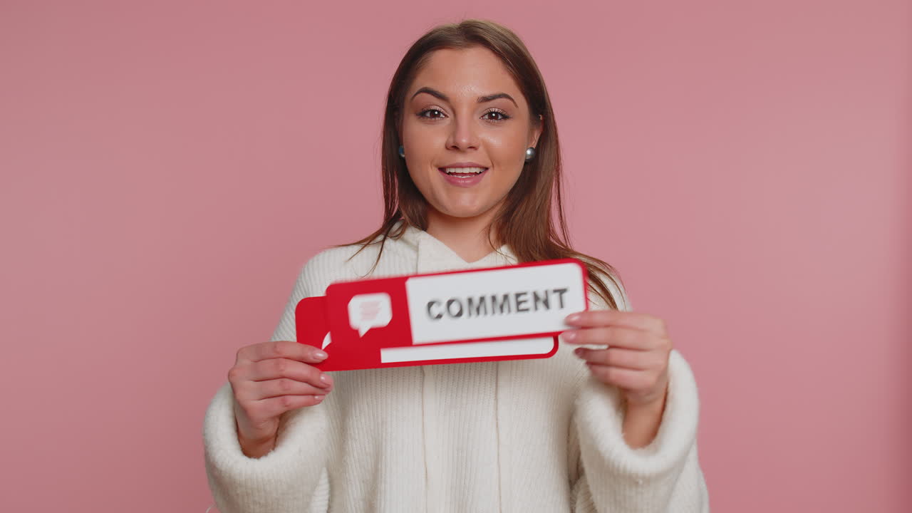 Smiling woman in white sweater poses against pink background