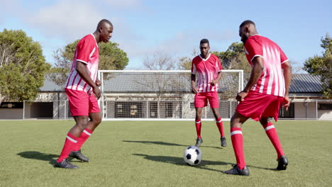 playing soccer on field, three african american men in red uniforms practicing teamwork skills