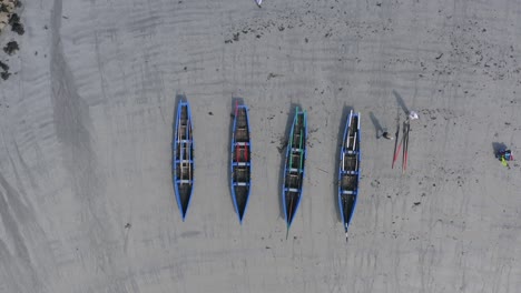 static bird's eye view of currach boats on sandy beach as workers separate oars