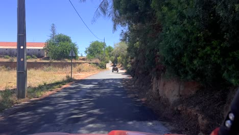 point of view driver driving on quadbike through the roads of algrave portugal