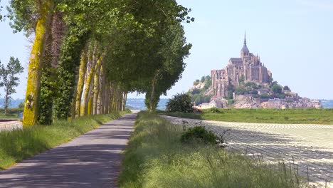 a pretty road through the countryside with mont saint michel monastery island in distance normandy france