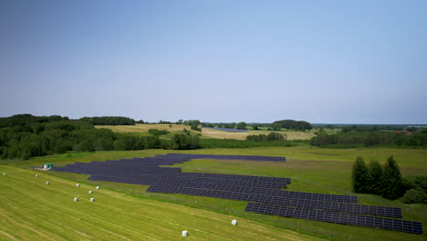 ascending aerial view of eco-friendly solar panels on green field in poland during beautiful sunny day and blue sky