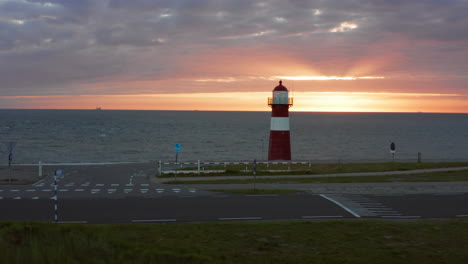 el faro de westkapelle durante una puesta de sol naranja brillante, con mucho viento