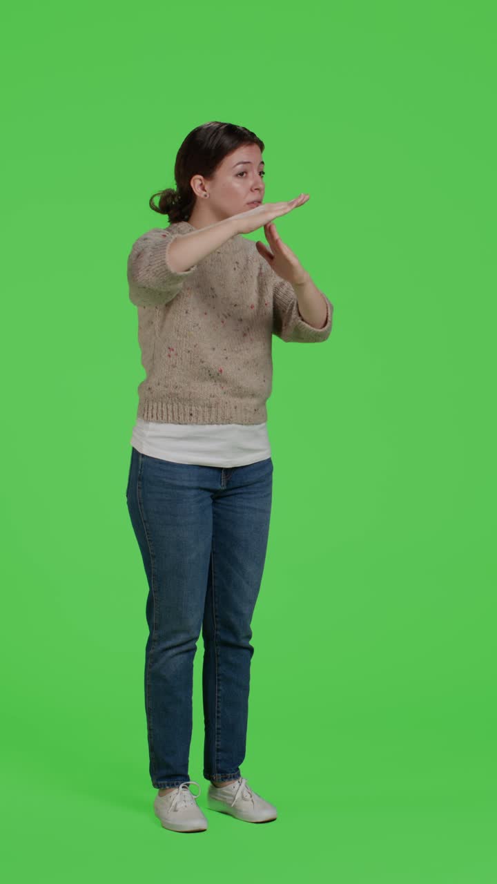 Dikey video: Yeşil ekranda T şeklinde sembol yapan bir kişinin yandan görünümü (tam vücut)