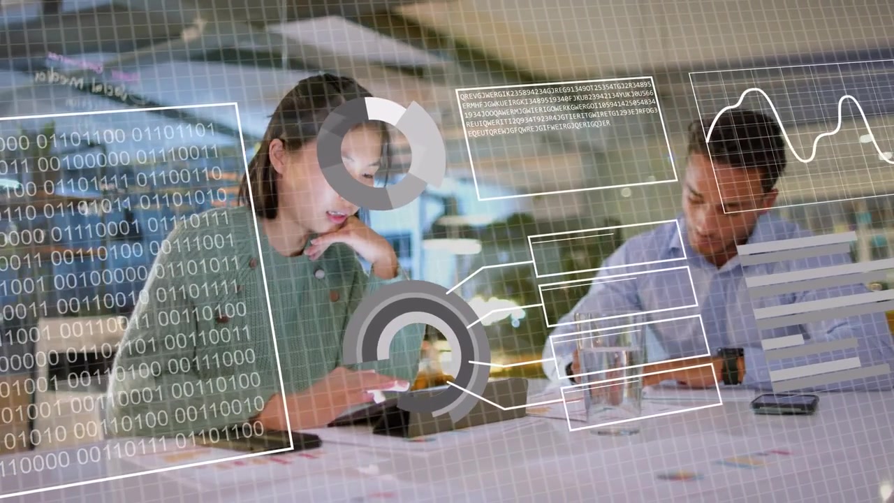 Data overlay appearing over tablet, woman tapping and man writing while reviewing business charts