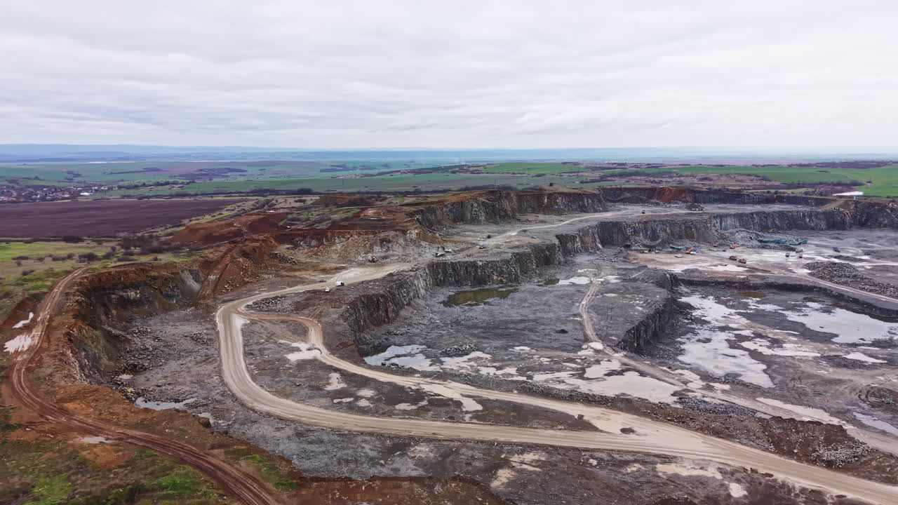 Granite quarry excavation site with machinery and cleared paths in action during cloudy daytime