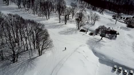 aerial - drone shot of chairlift carrying skiiers up snowy mountain