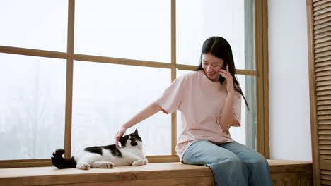 창가에 고양이를 데리고 있는 여자