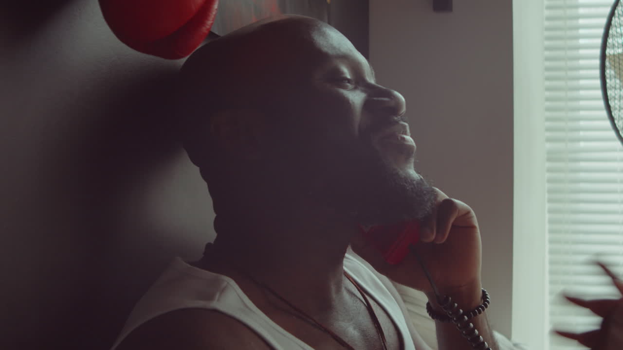 아프리카계 미국인 남자가 침실에서 전화로 채팅하고 있습니다.