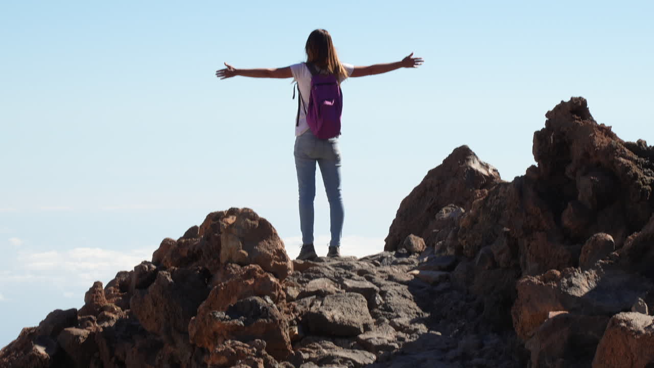 Female hiker with open arms enjoying breathtaking panorama on top of mountain in Tenerife, Teide, Canary Islands