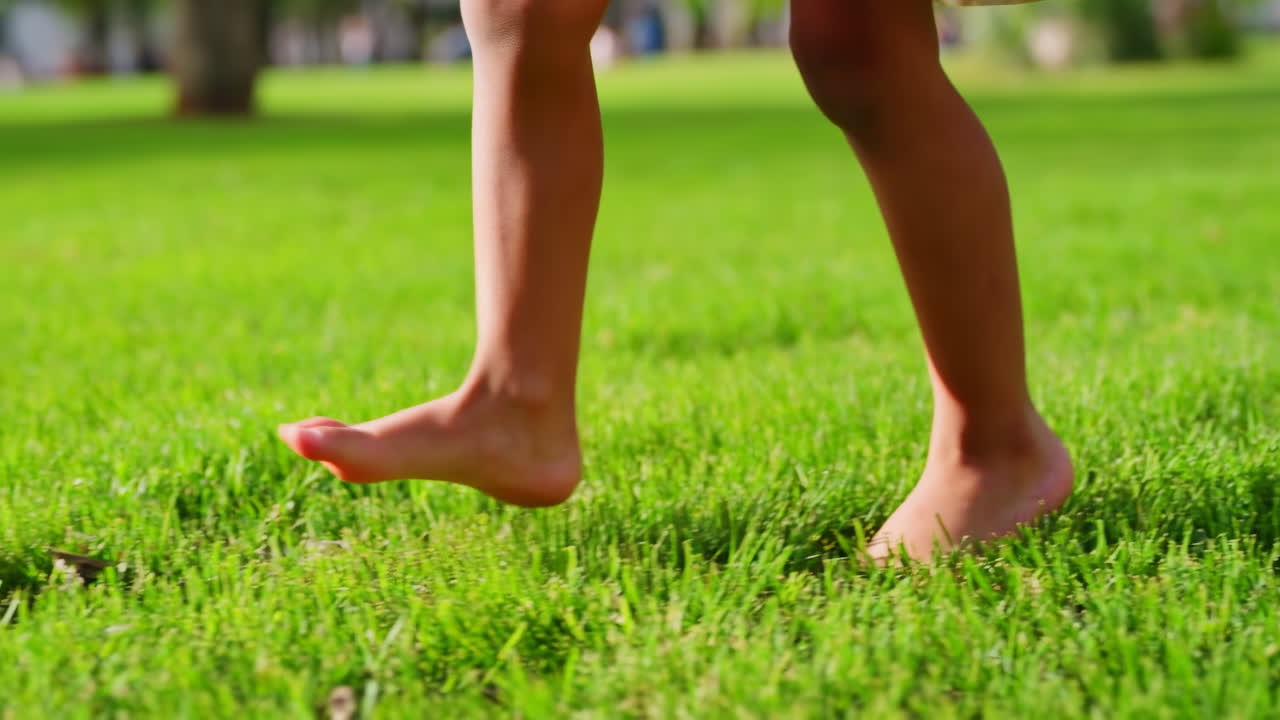 Little Child's Bare Feet Stepping on Fresh Green Grass