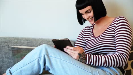 Woman-using-digital-tablet-on-sofa-at-home-4k