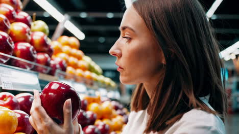 woman choosing an apple in a grocery store