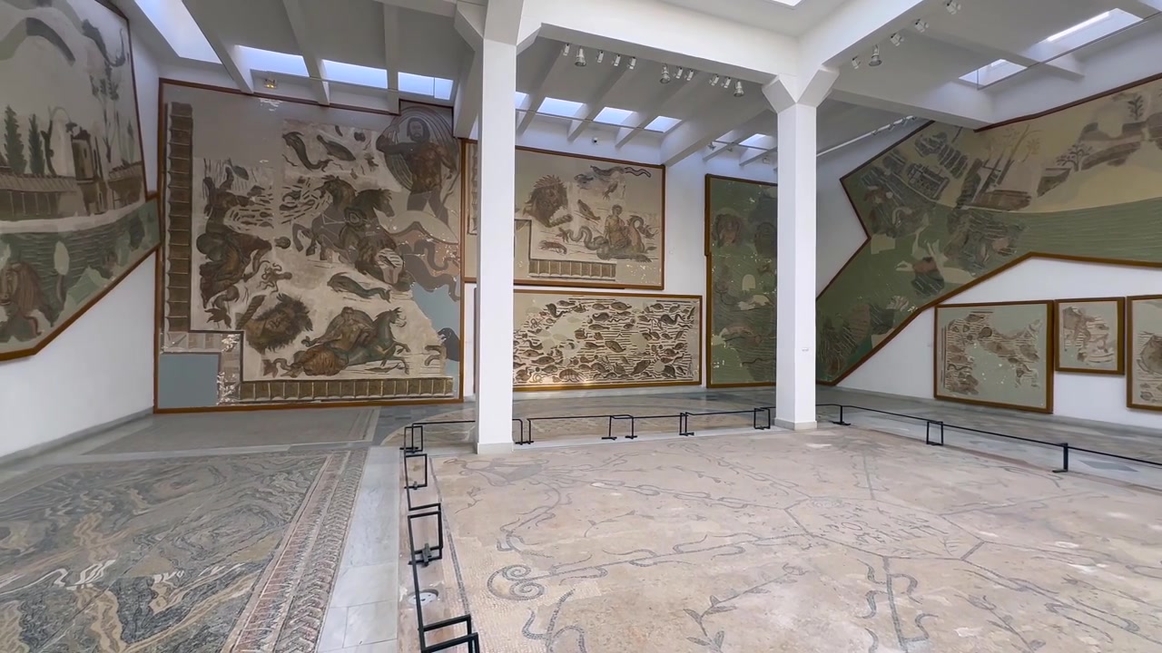 Pannelli a mosaico romano coprono le pareti di una luminosa galleria con un pavimento centrale aperto nel Museo Nazionale del Bardo. Tunisia