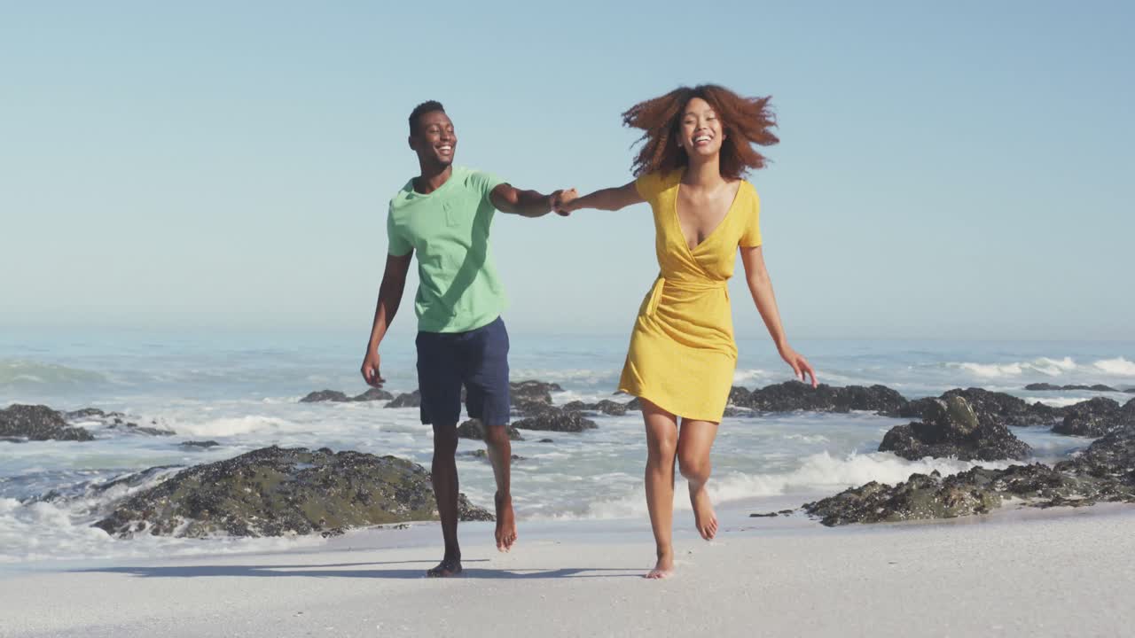 African American couple running side by side at beach