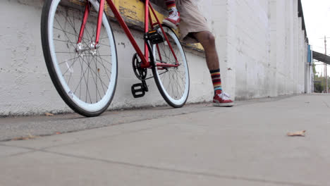 slider shot of a black man with his red bicycle in an industrial setting