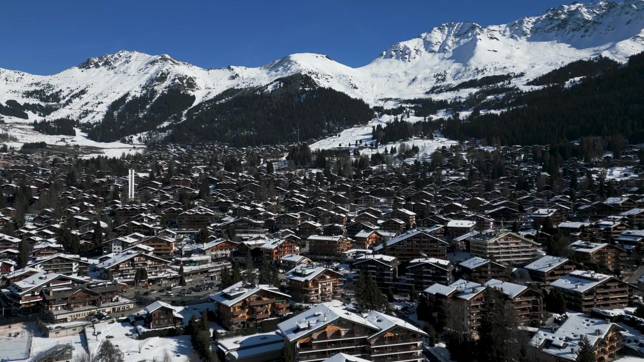 Veduta aerea grandangolare che si avvicina alla città di Verbier in Svizzera in una giornata limpida e soleggiata